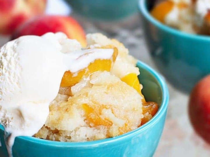 A delectable bowl of peach cobbler topped with a scoop of creamy ice cream and fresh peaches
