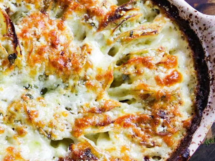 A dish of cheesy roasted cauliflower on a wooden table.