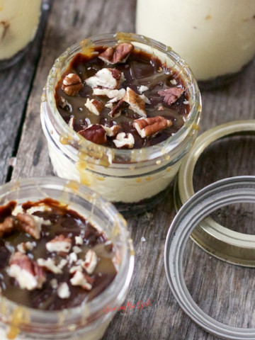 Pecan cheesecake in jars on a wooden table.