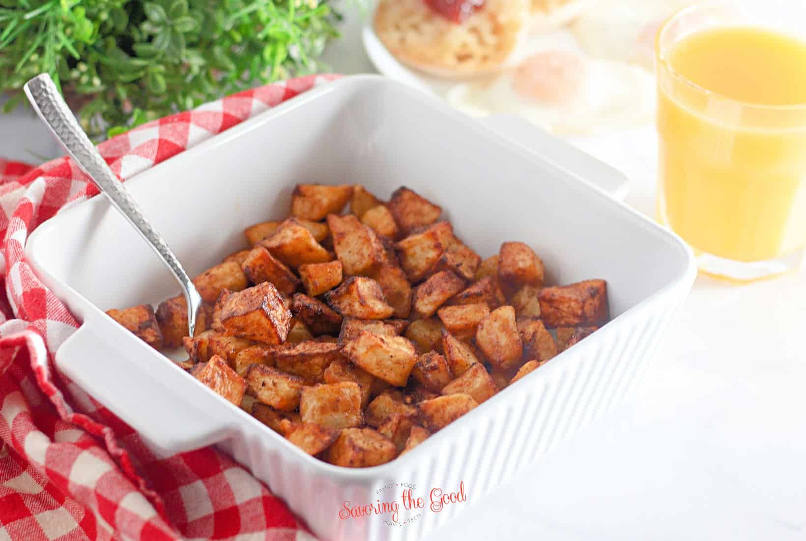 Air fryer breakfast potatoes horizontal image in a white serving bowl and a serving spoon.