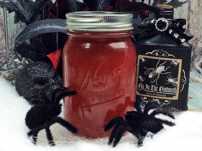 A mason jar with spiders and a bottle of liquor.