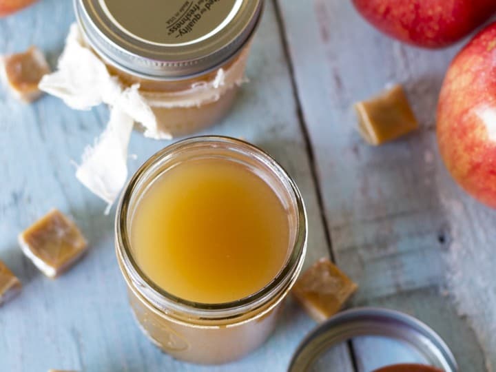 Apple butter in a jar and apples on a table, perfect for making delicious moonshine recipes.