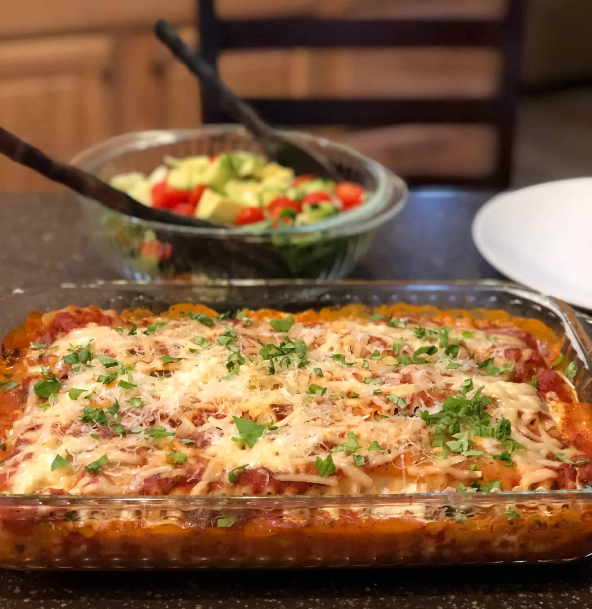 A mouthwatering dish of lasagna and a refreshing salad beautifully presented on a counter.
