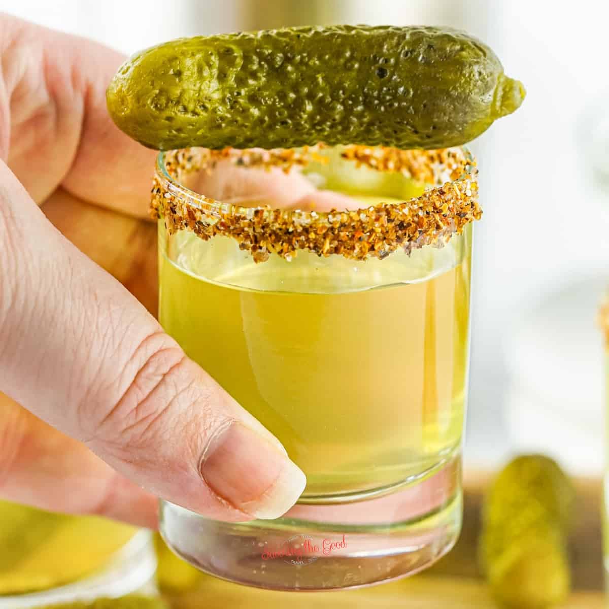 Pickle shot with mini pickle garnish, seasoned rim.