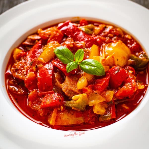 vegan sausage red stew in a white bowl.