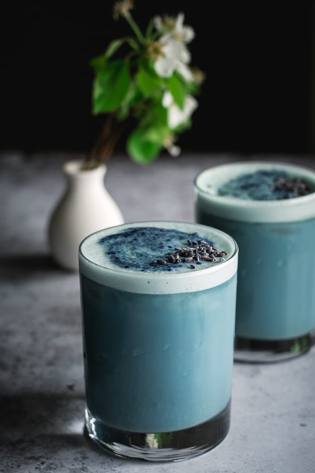 Two glasses of blue latte on a table.