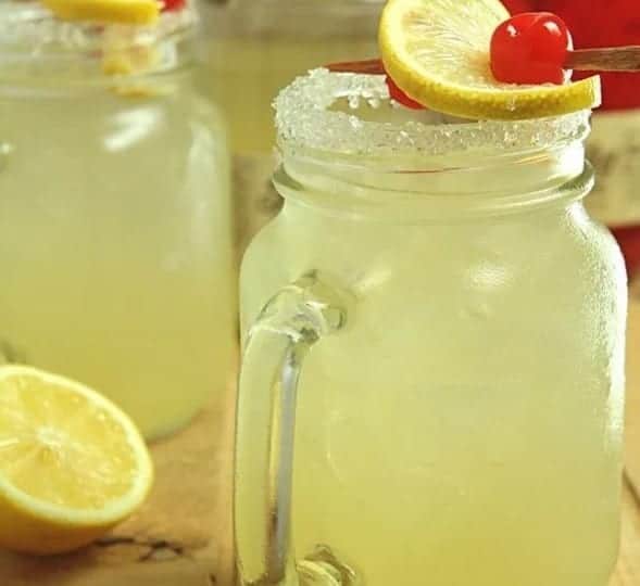 Two mason jars filled with homemade moonshine lemonade and cherries.