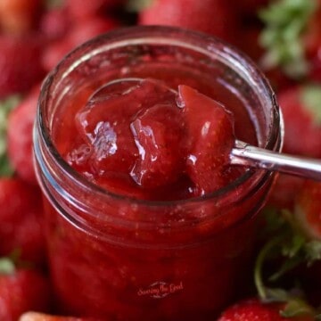 square image of saucy strawberry topping in a jar with a spoon taking out a portion.