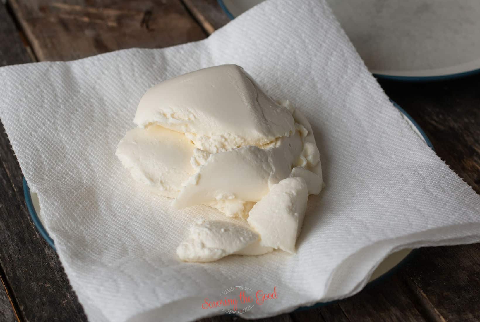whole milk ricotta cheese resting on a paper towel to drain.