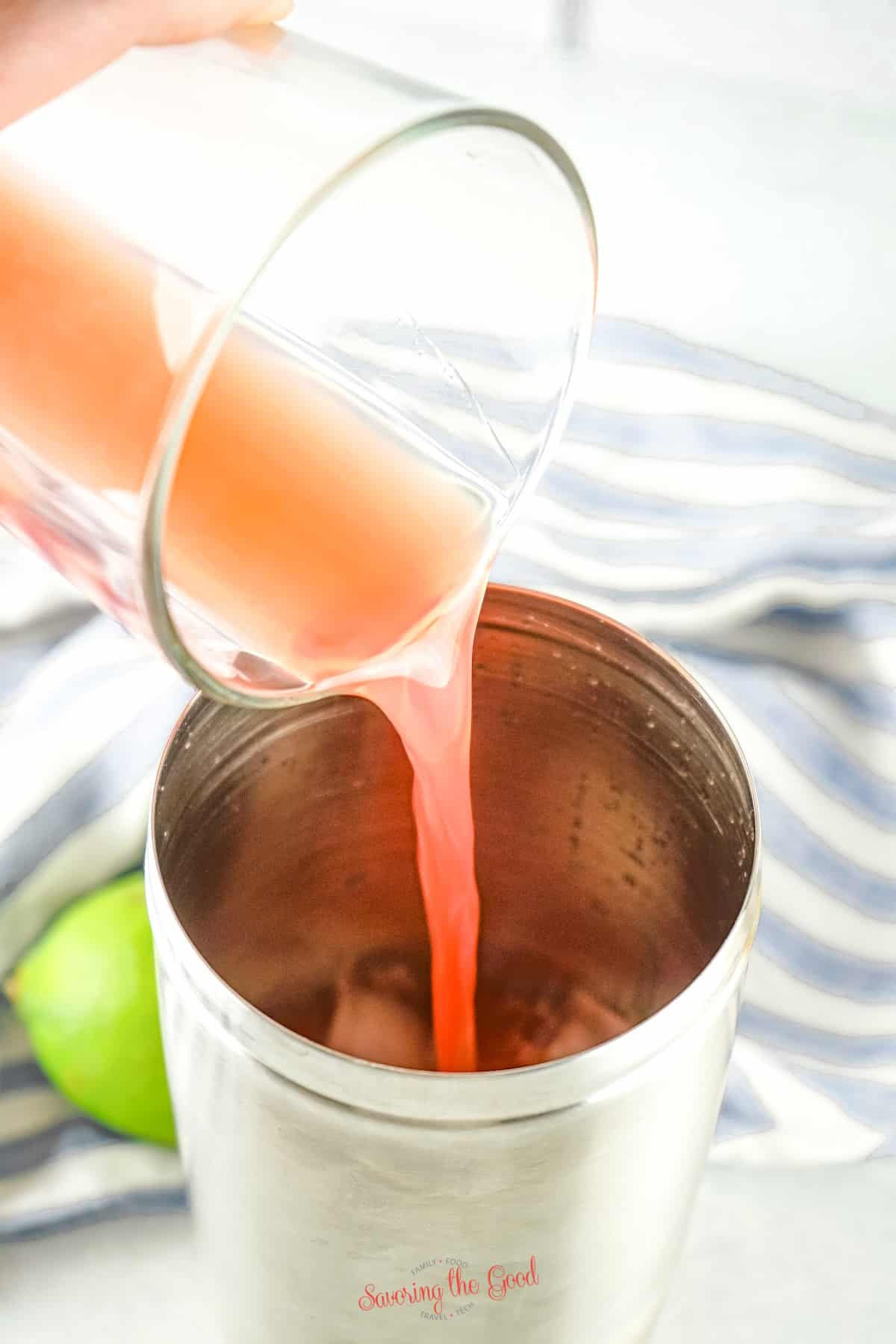cocktial juice being poured into the cocktail shaker with ice.