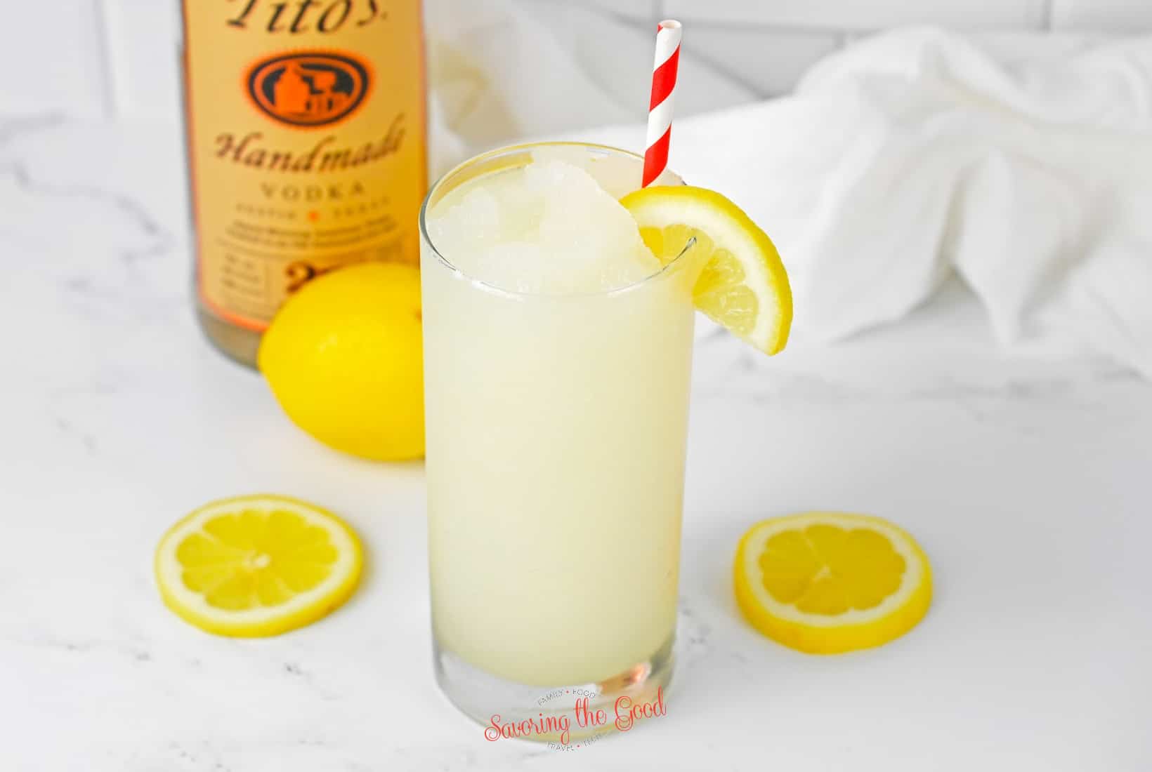 frozen lemoade with vodka slush in a clear glass with lemon wedge garnish.