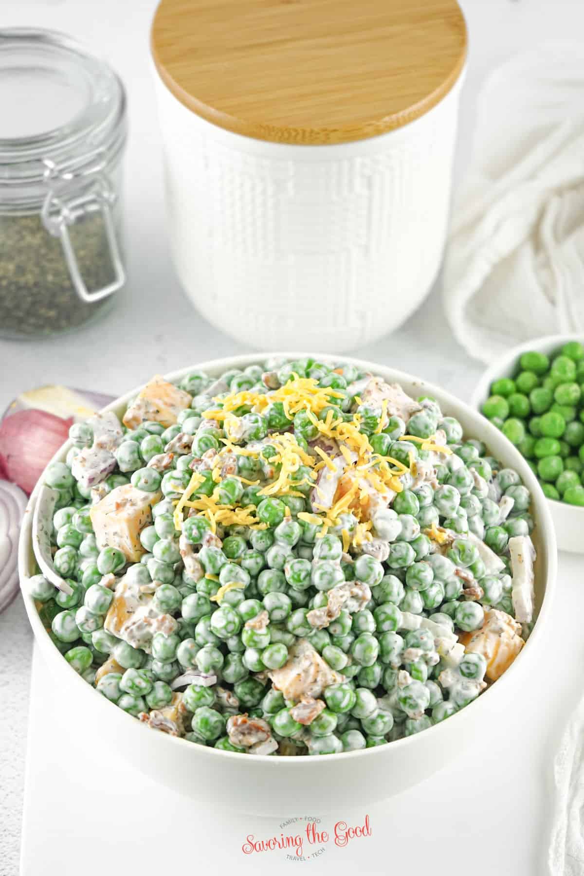 pea salad in a bowl with kitchen accessories in the background.