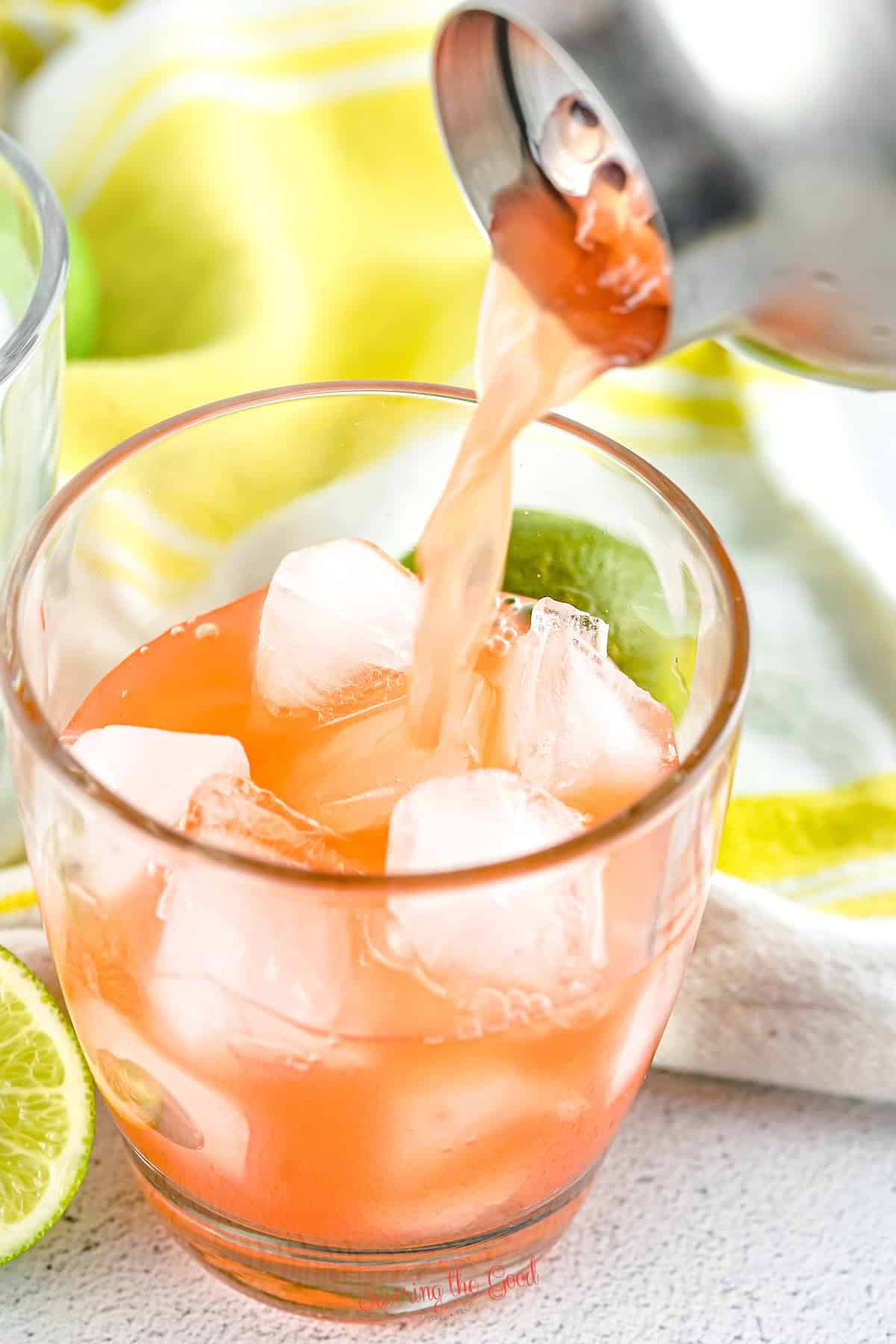 rum punch being poured into a class with ice.