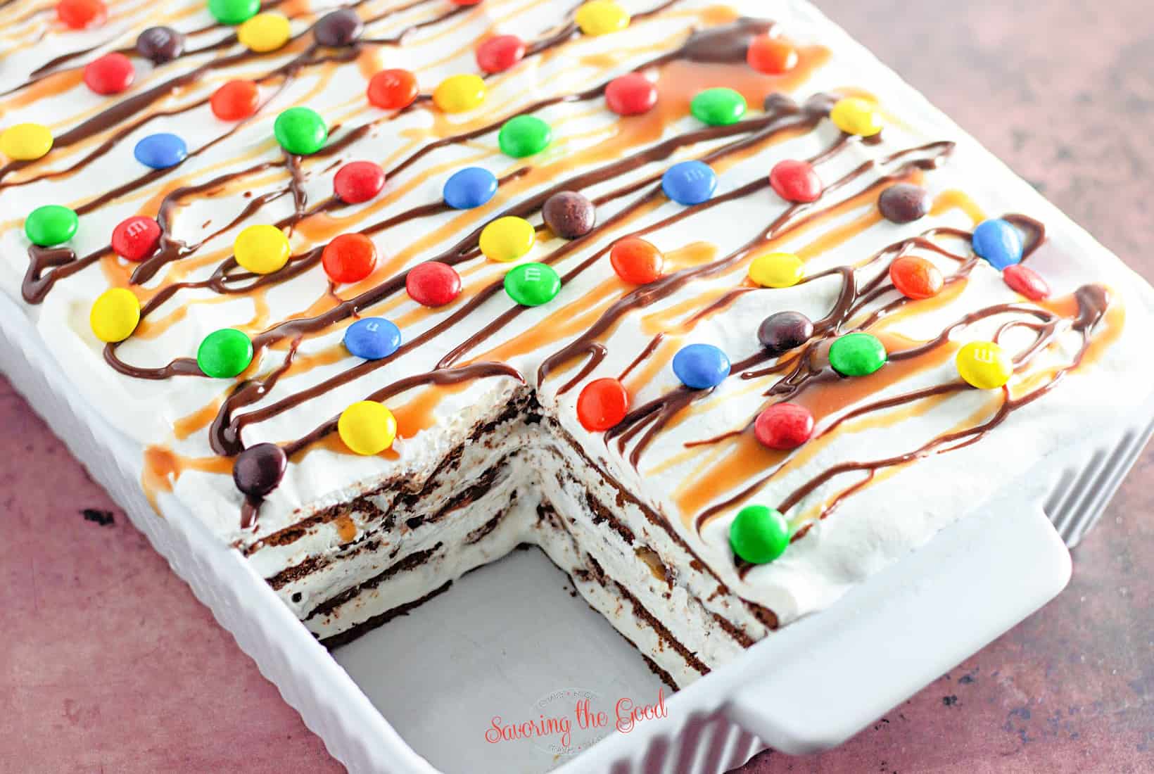 horizontal image of ice cream bar cake with a slice taken out of it in a white 9x13 pan.