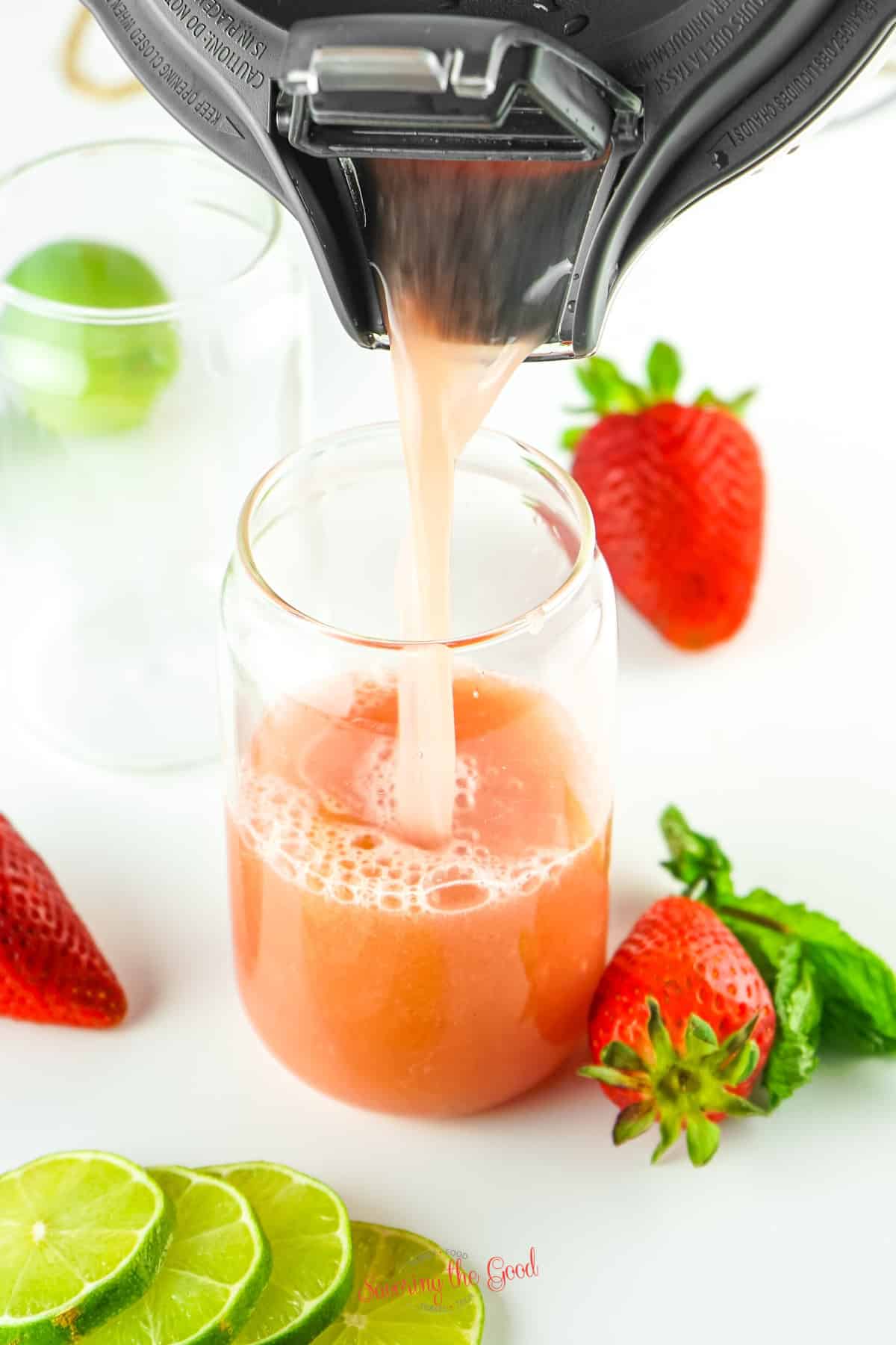 strawberry agua fresca being poured into a clear glass.