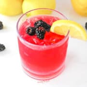 blackberry lemonade in a glass with garnishes.