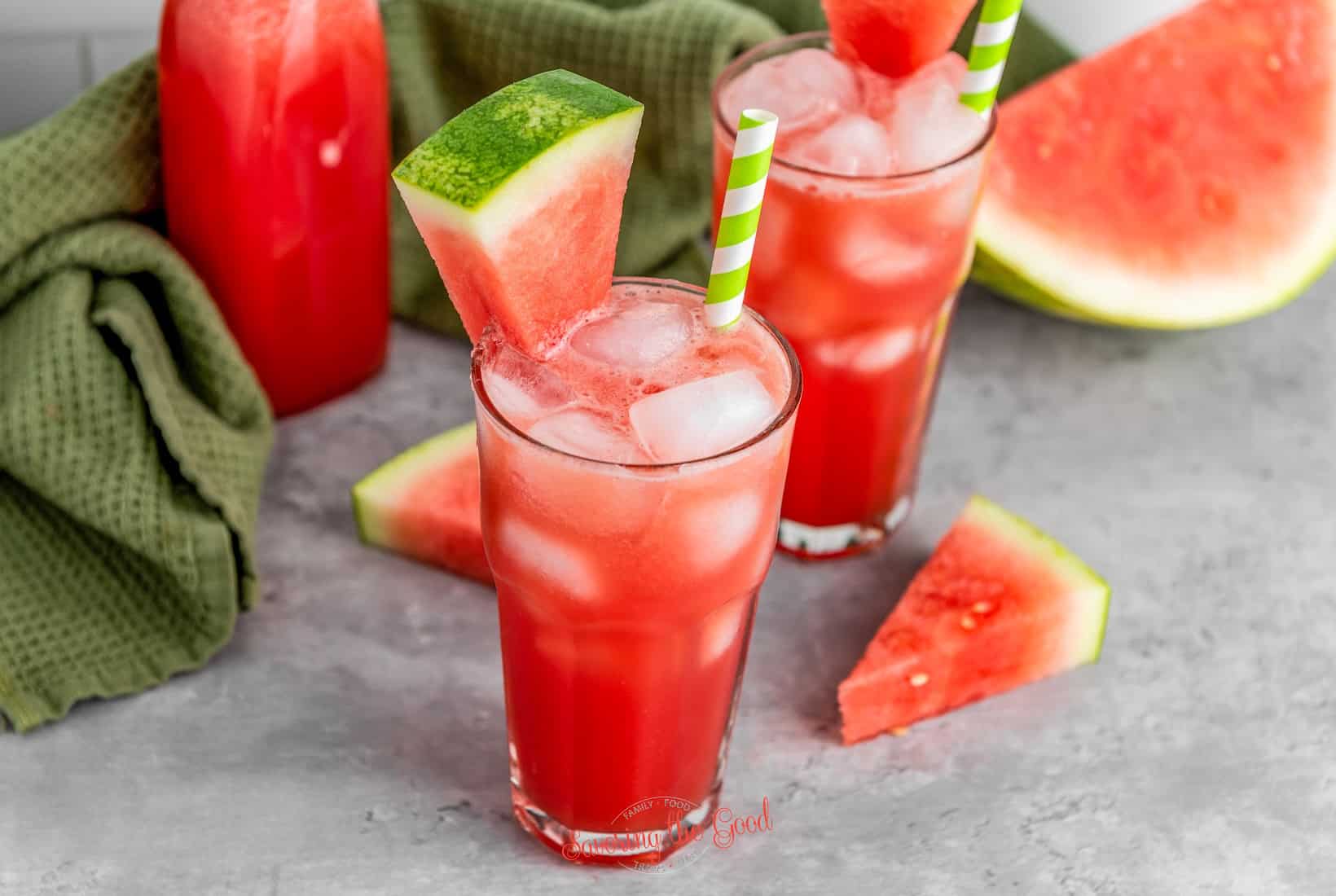 horizontal image of a glass of watermelon juice with ice and a garnish of watermelon wedge.