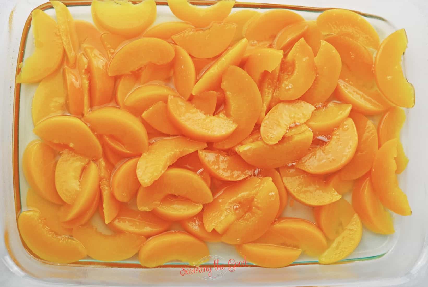 peaches added to a glass baking dish for peach dump cake .