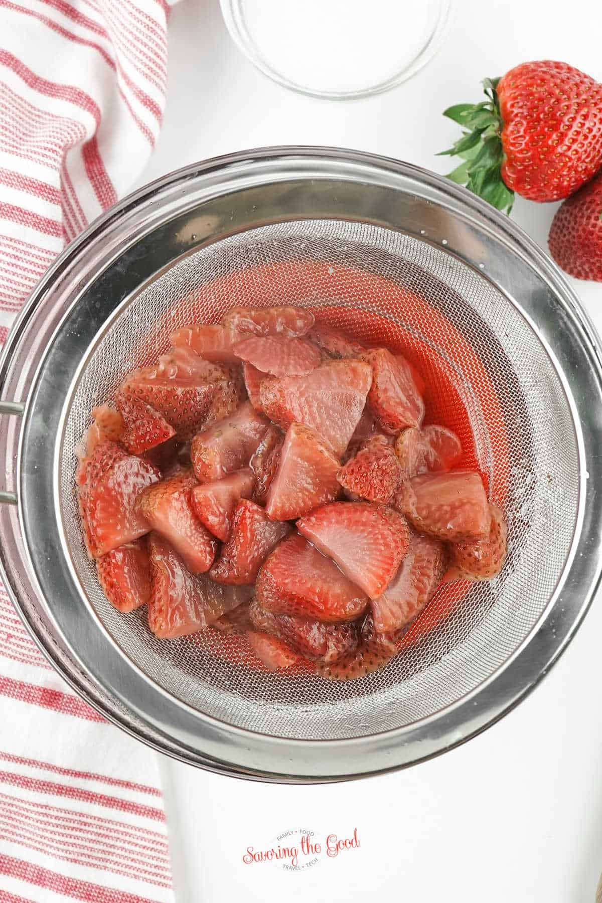 mashed, strained, cooked strawberries in a strainer.