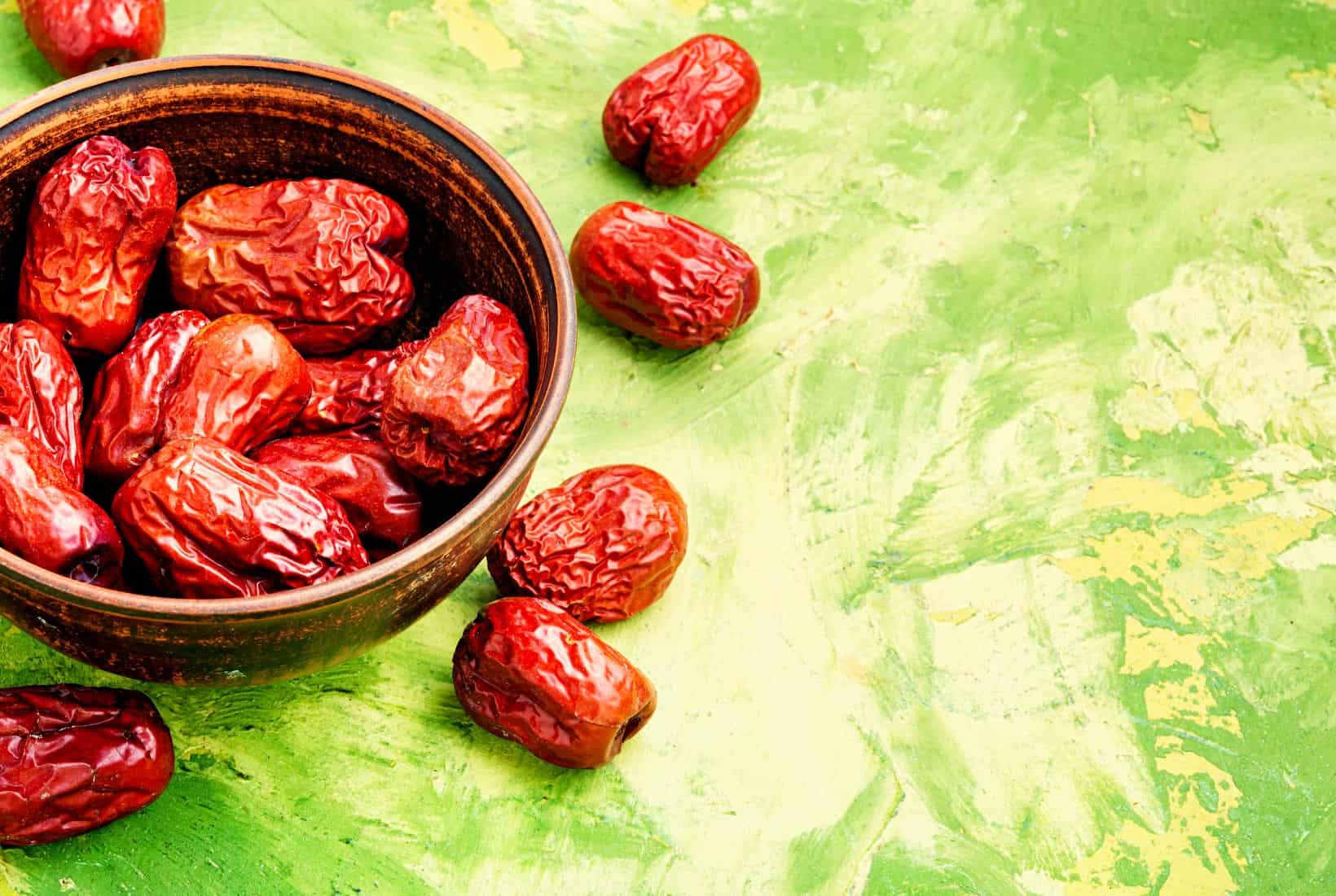 chinese dates in a bowl on a green background.