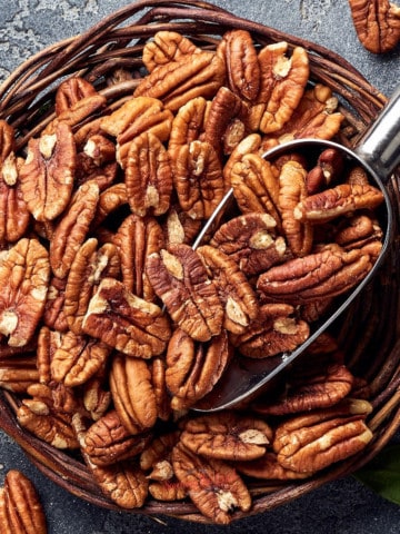 Pecans in a bowl with a spoon.as featured image of pecan recipes.
