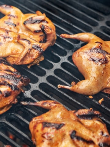 A group of quails are being cooked on a grill.