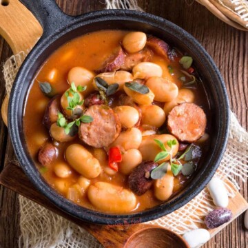 Sausage and beans in a skillet on a wooden table featuring Polish Breakfast ideas