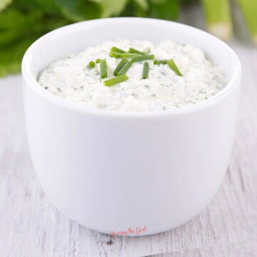 A white bowl of dip with celery and chives.
