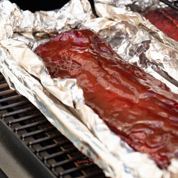 Bbq ribs in foil on a grill.