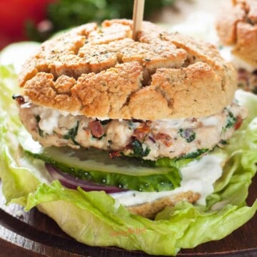 A turkey burger with lettuce and tomatoes on a wooden board.
