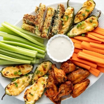 A plate with celery, carrots, celery sticks and dip.