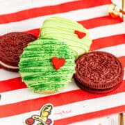 Three chocolate covered Oreo cookies on a red and white striped napkin.