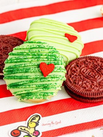Three chocolate covered Oreo cookies on a red and white striped napkin.