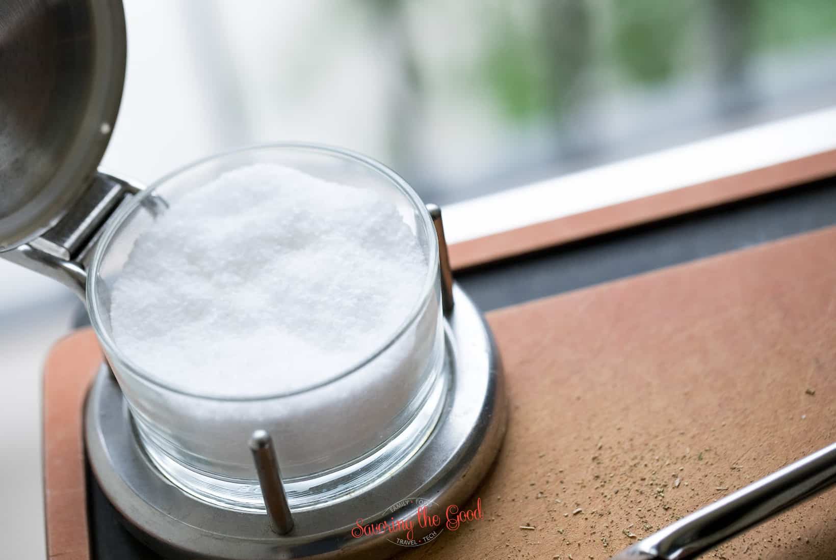 A glass of salt sitting on a cutting board.