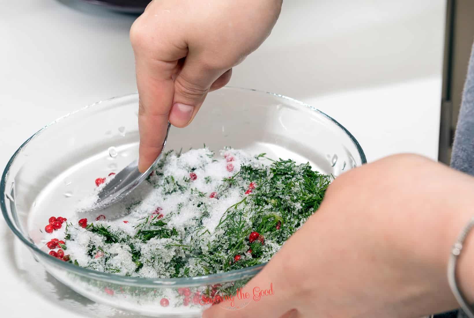 A person mixing greens and pomegranate in a bowl.
