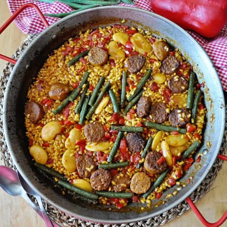 Paella with sausage and beans in a pan.