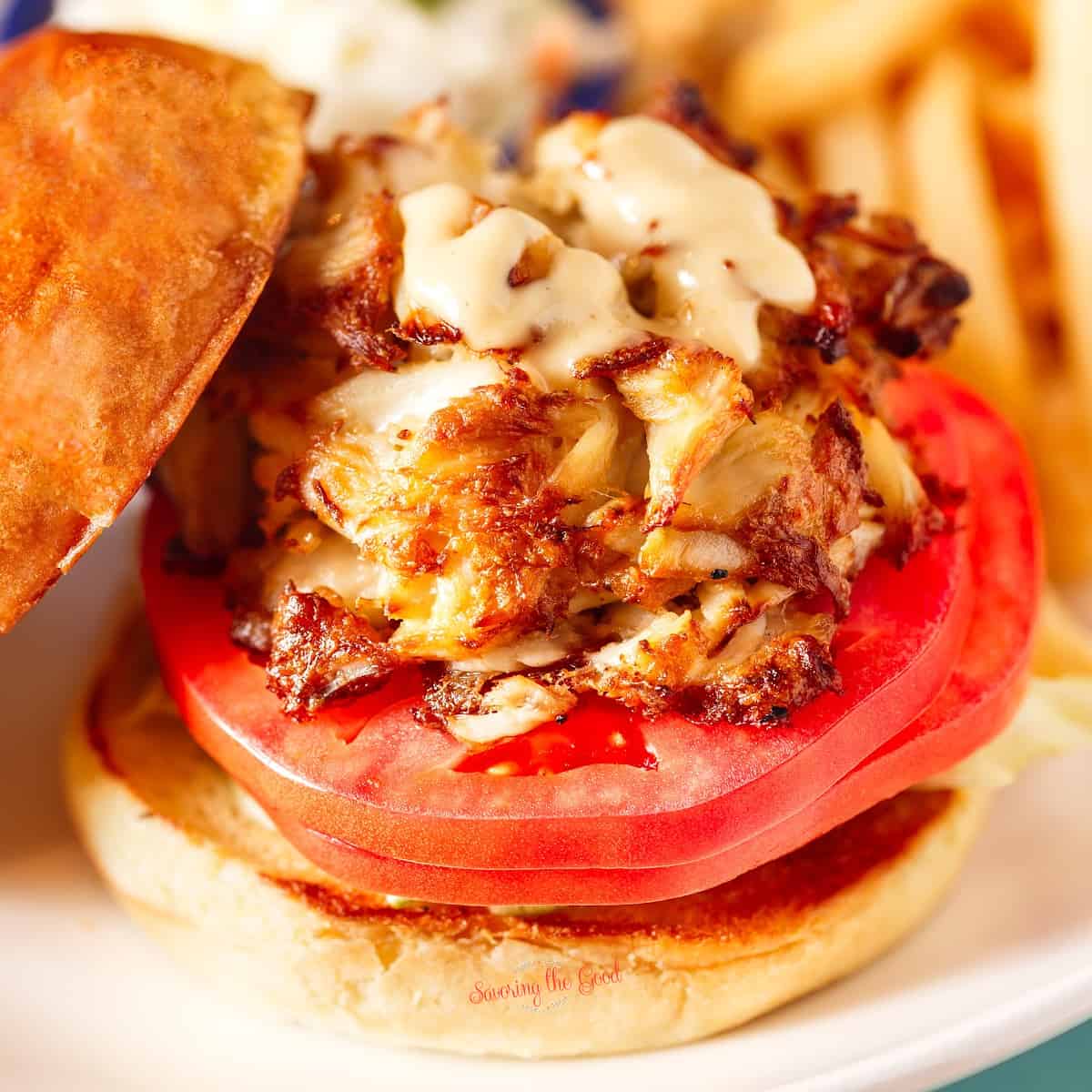A crab cake burger on a plate with french fries.