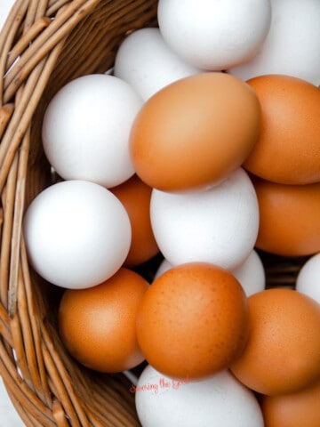 White and brown eggs in a wicker basket, showcasing 100 ways to prepare an egg.