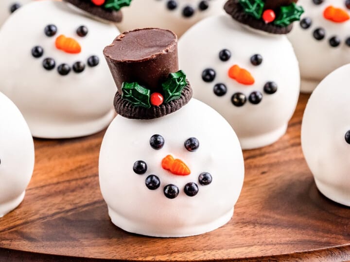 Snowman chocolate truffles on a wooden board.