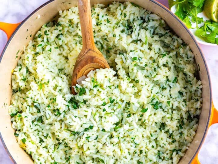 A pot filled with cilantro lime rice, with a wooden spoon placed inside, makes a perfect side dish when considering what to serve with sea bass.