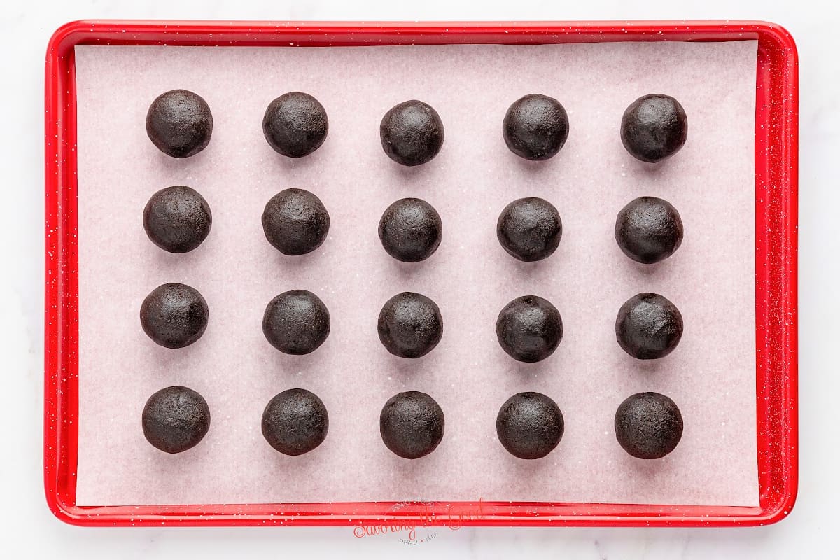 Chocolate truffles in a red tray on a white background.
