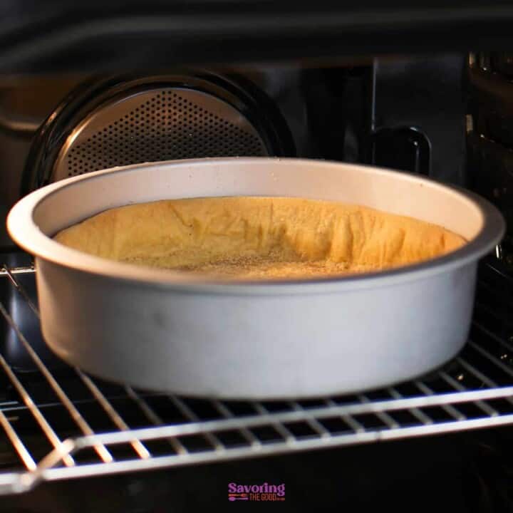 a sunken yellow cake in a pan in an oven.