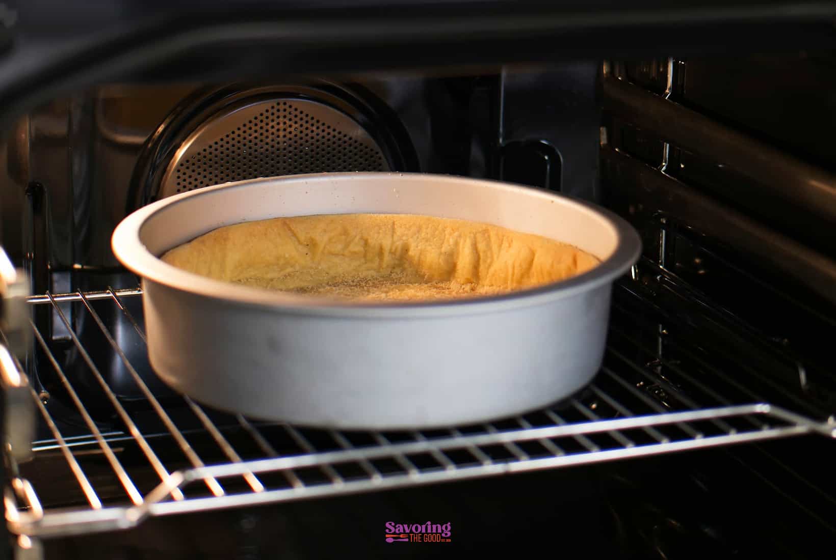 a sunken yellow cake in a pan in an oven.