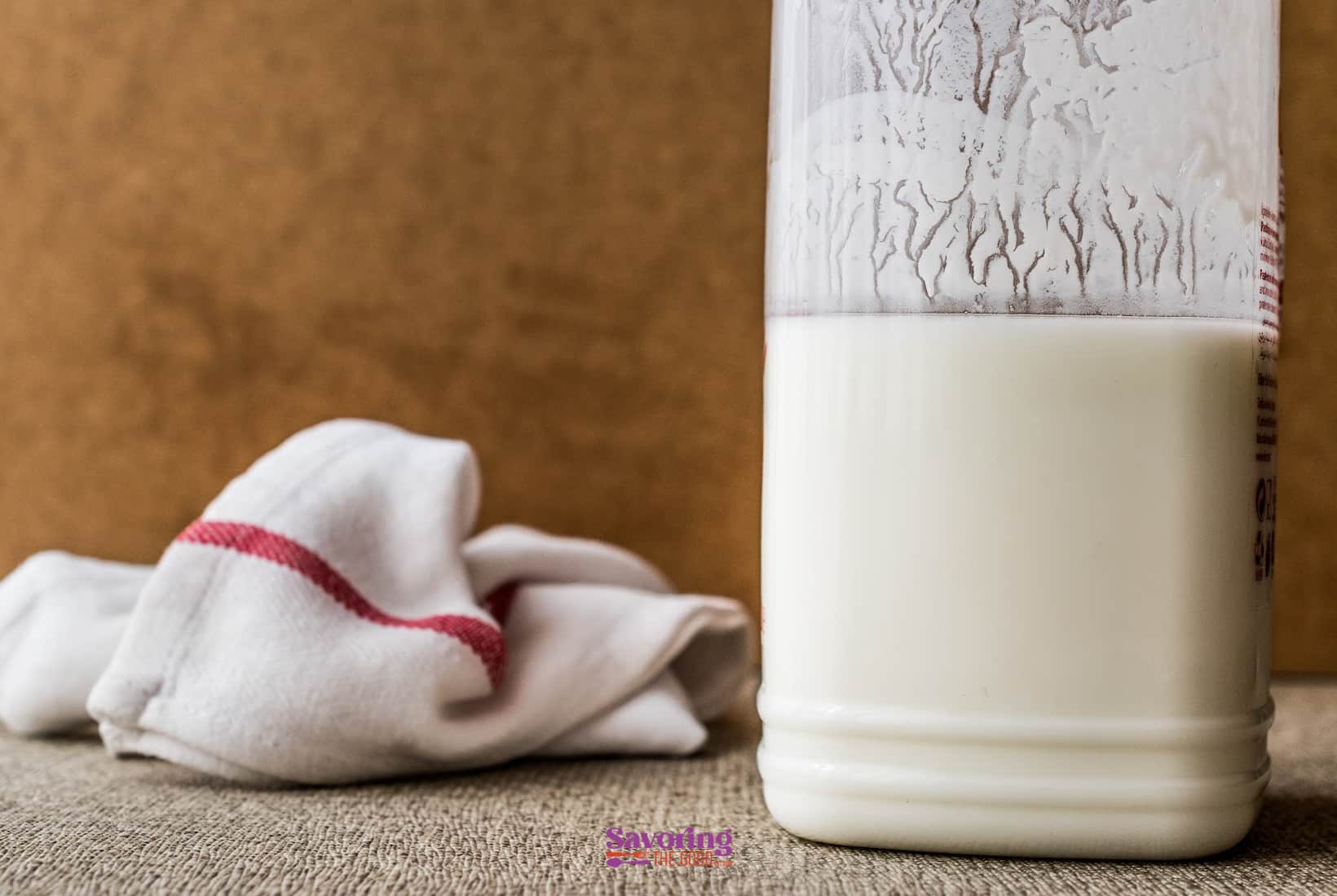 large glass jar of homemade buttermilk with a kitchen towel.