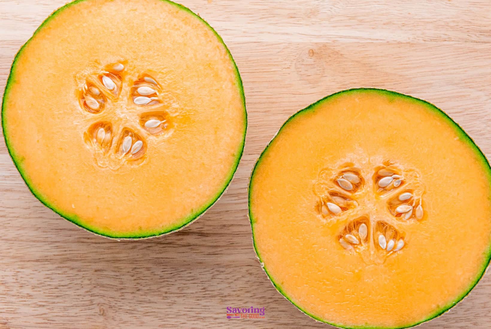Two halves of a cantaloupe on a wooden surface.