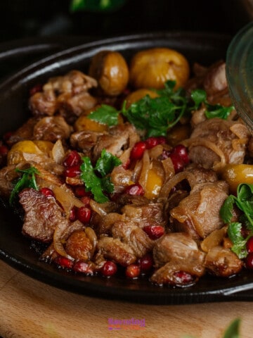 A skillet filled with chestnut  
and meat +onions.