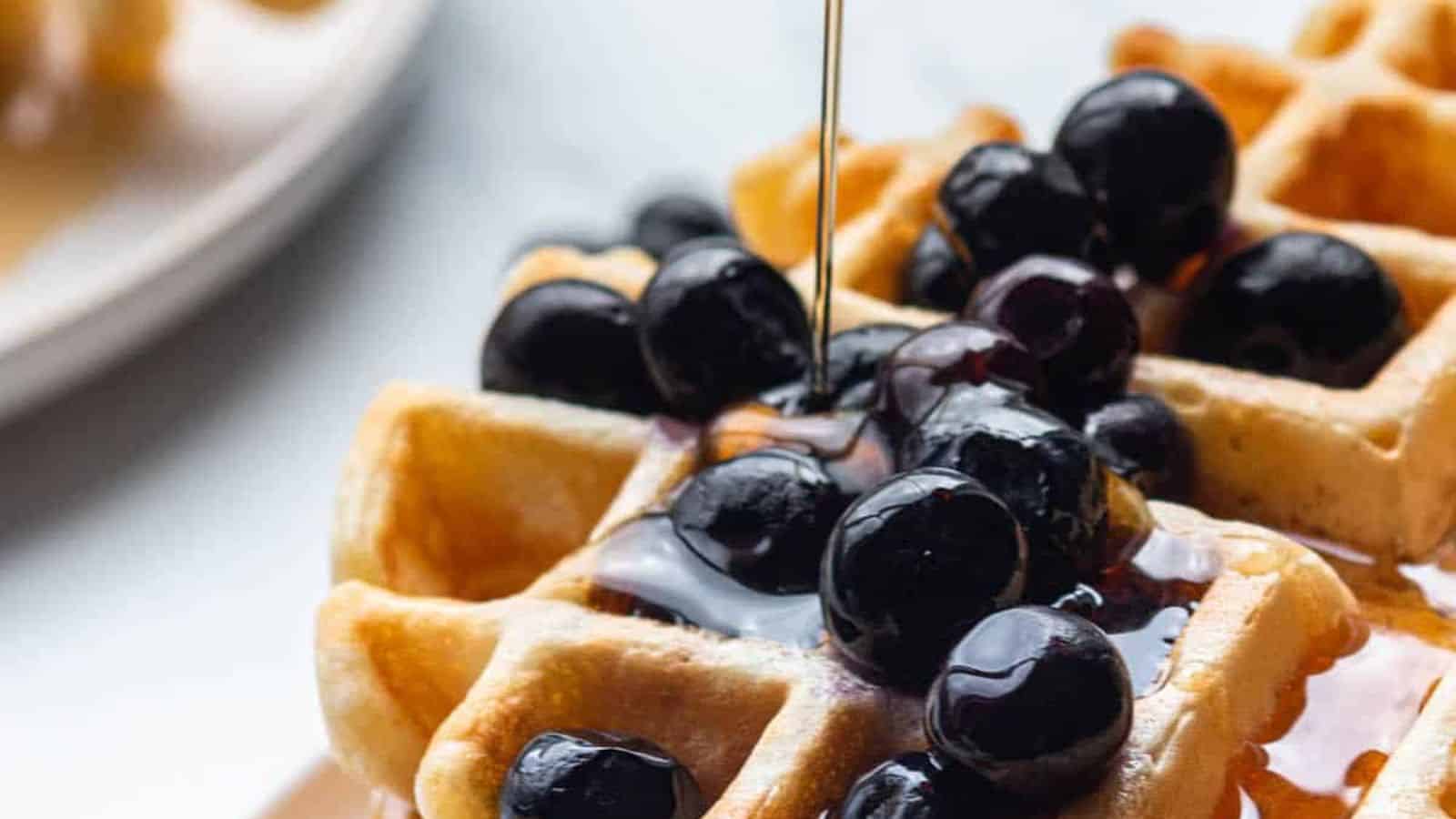 A waffle with blueberries and syrup.