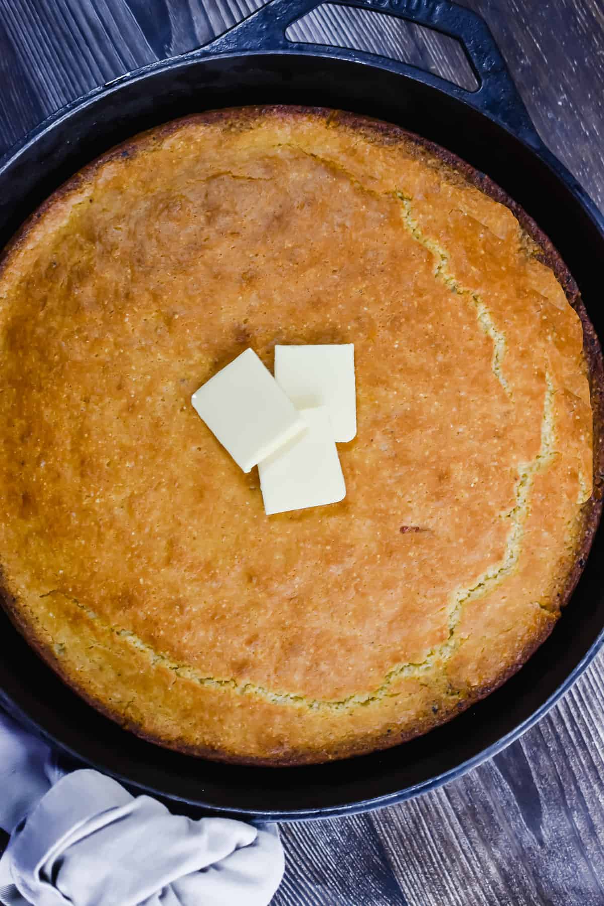 A slice of cornbread in a skillet with butter.