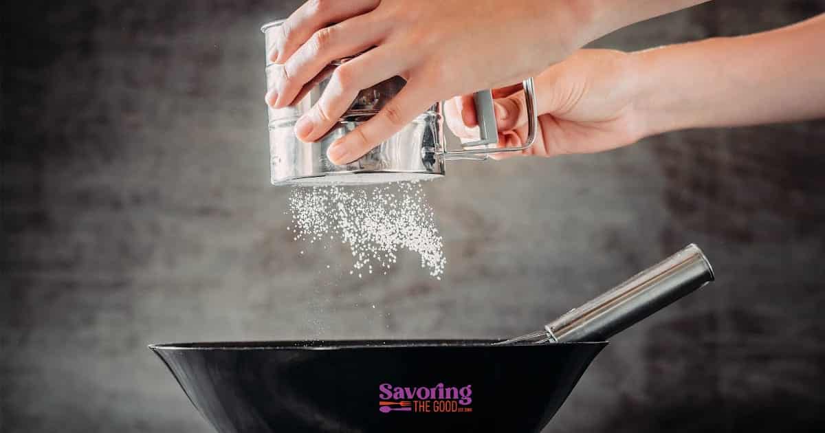 A person sifting flour into a bowl.