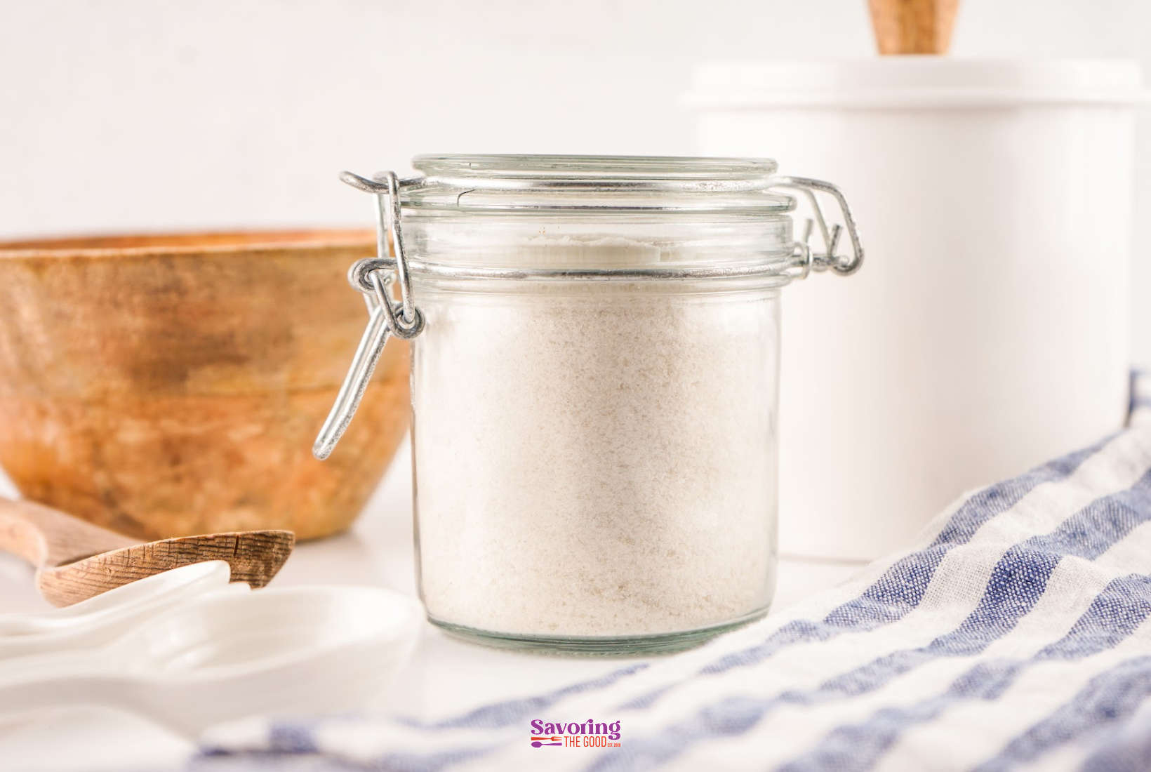 A jar of rice flour next to a spoon and a wooden spoon.